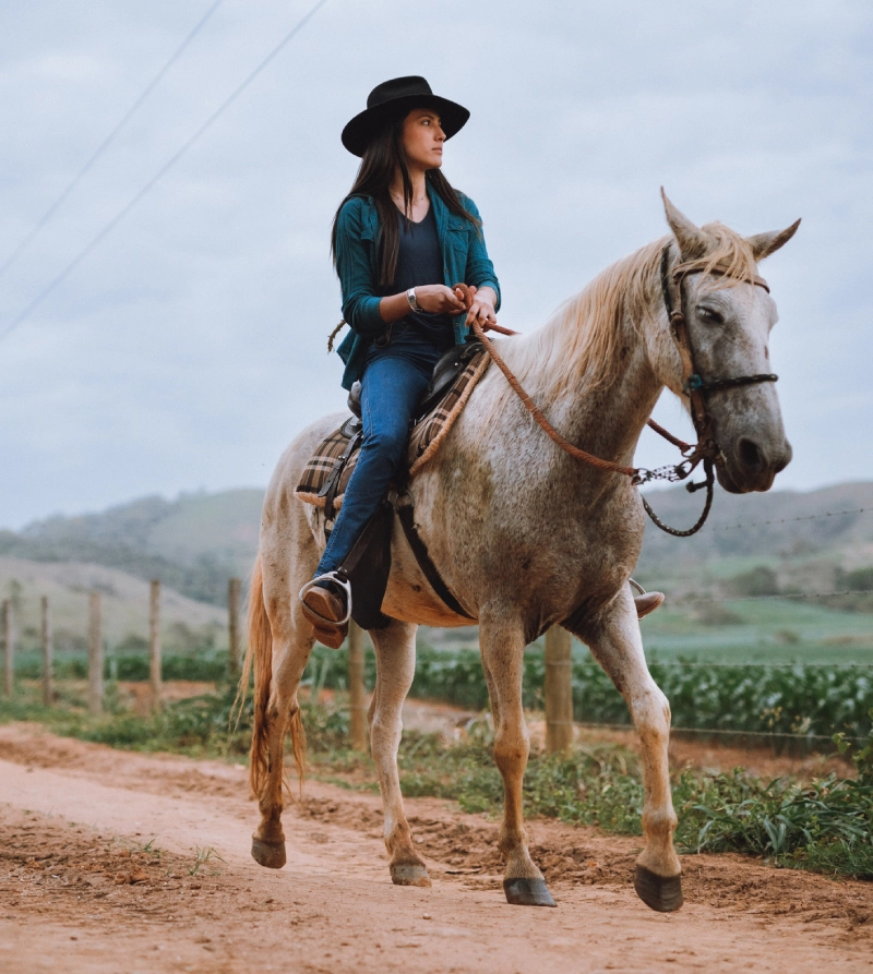 Woman riding horse on country dirt road