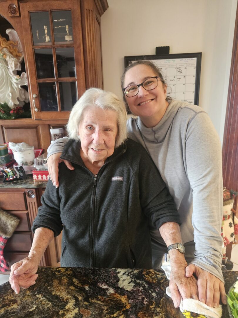 Two smiling women embracing at kitchen counter