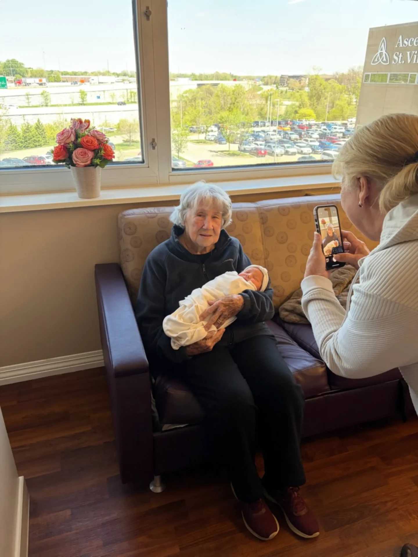 Woman holding baby in hospital while photographed