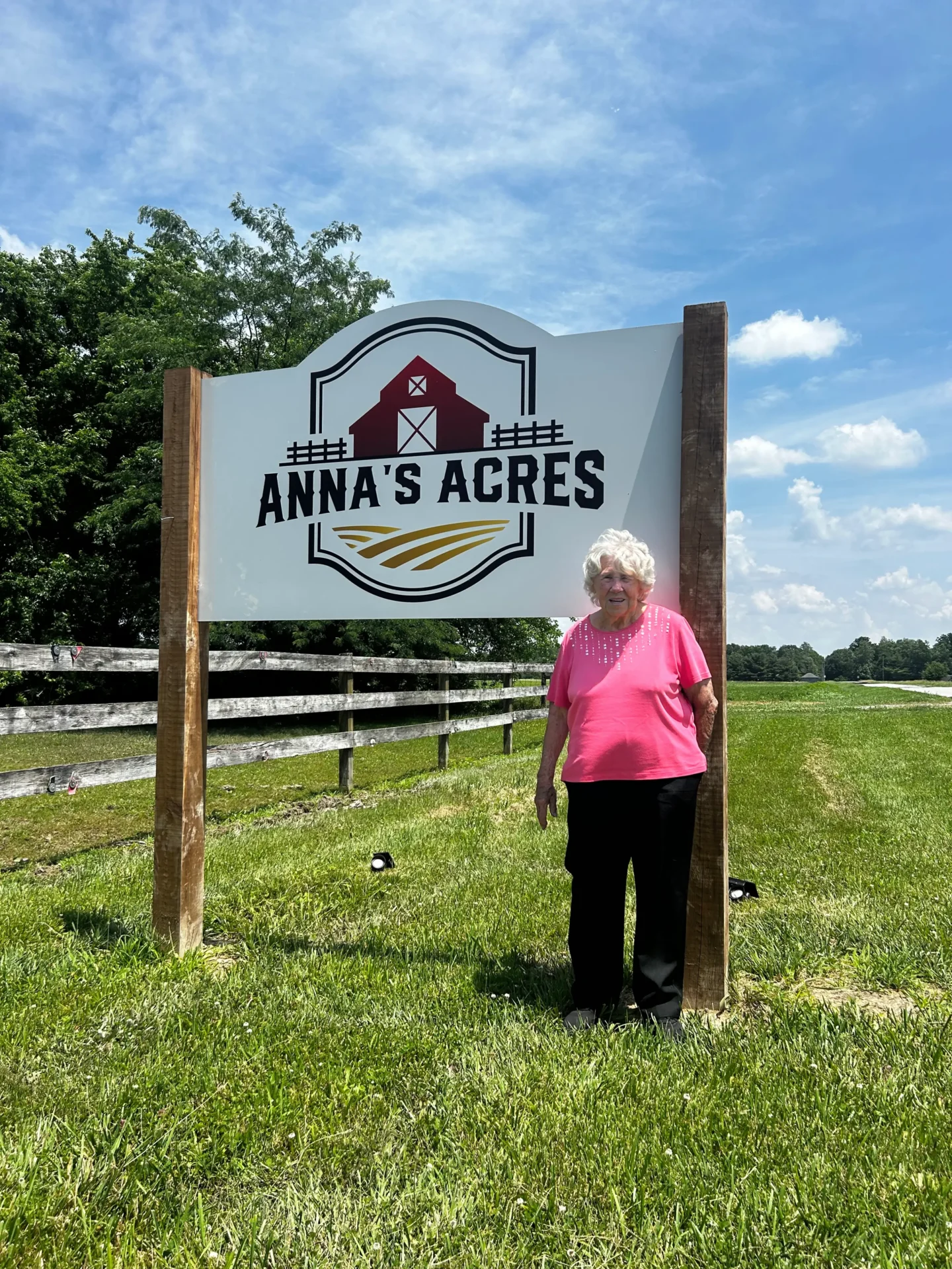 Woman standing beside Anna's Acres sign