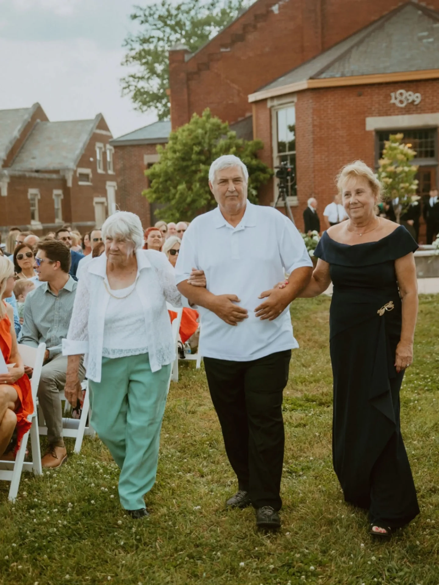 Three adults walking arm-in-arm at outdoor event