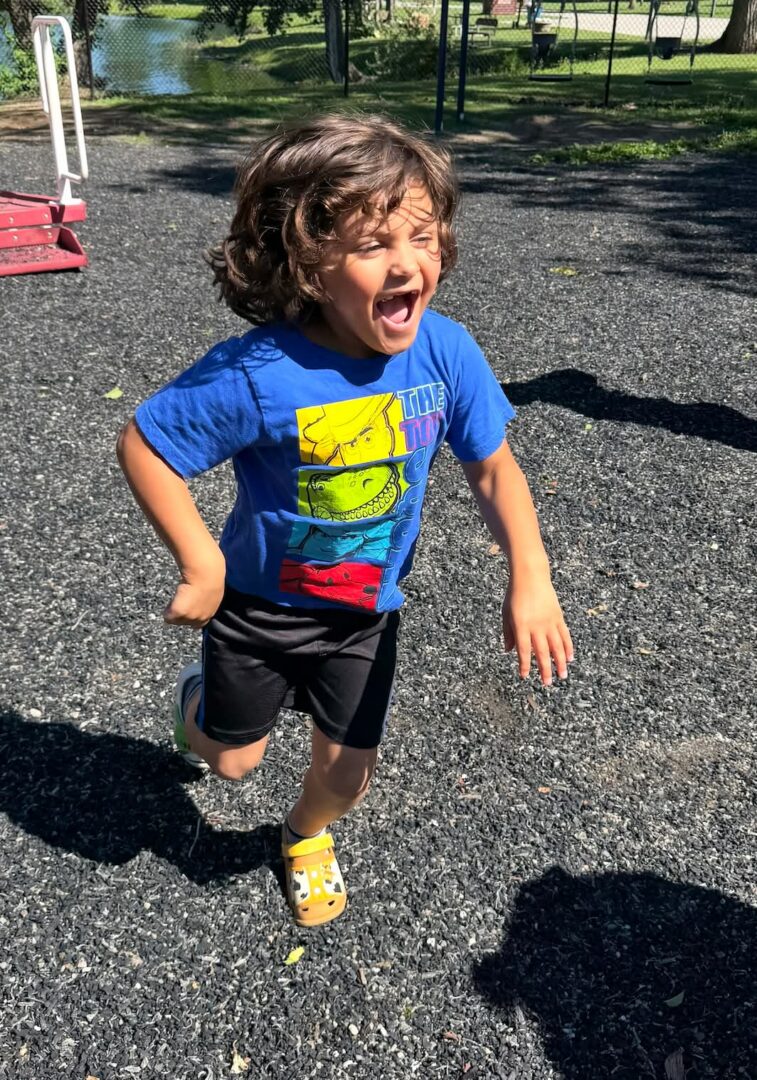 Curly-haired child running excitedly on playground
