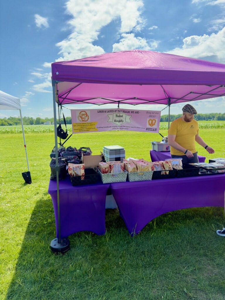 Purple market tent with vendor and baked goods