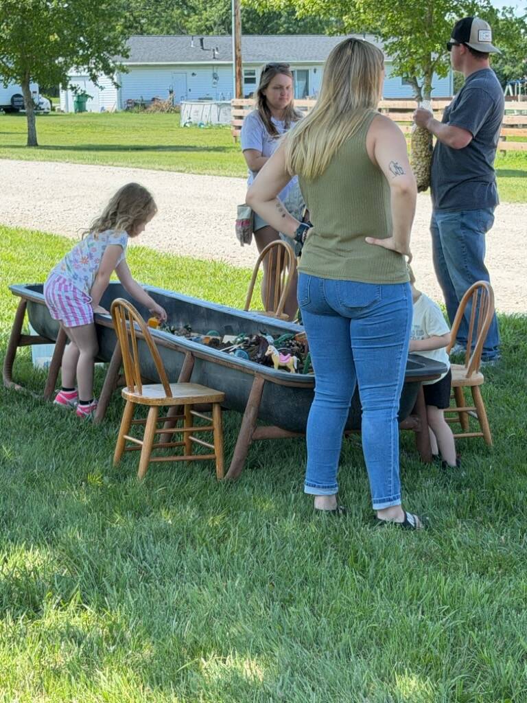 Adults and children around outdoor metal tub