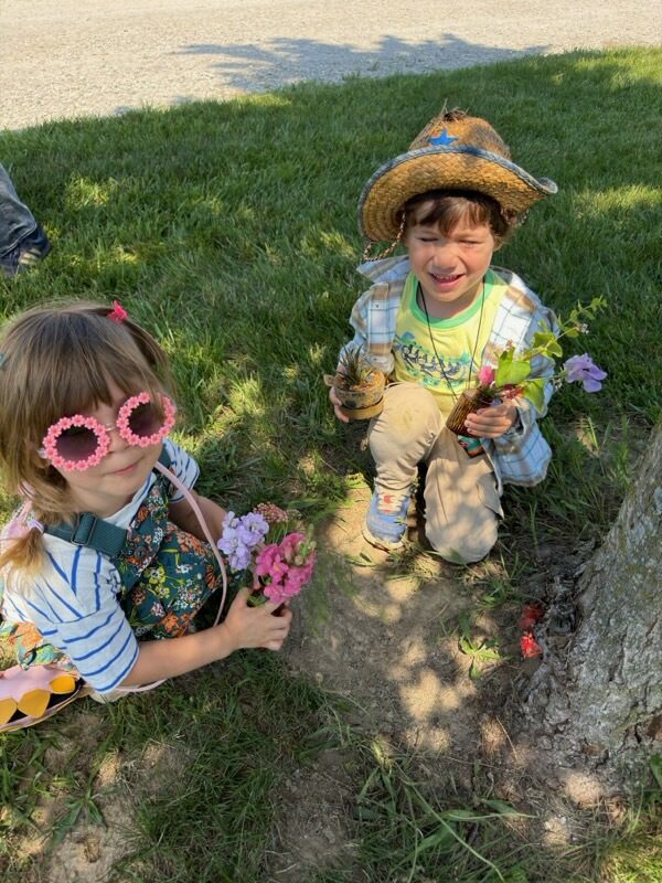 Two children with flowers under tree