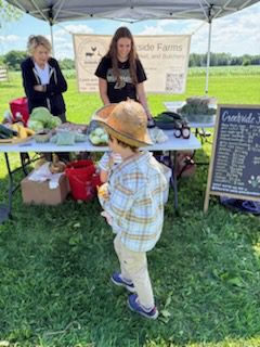 Child wearing straw hat at outdoor farm stand