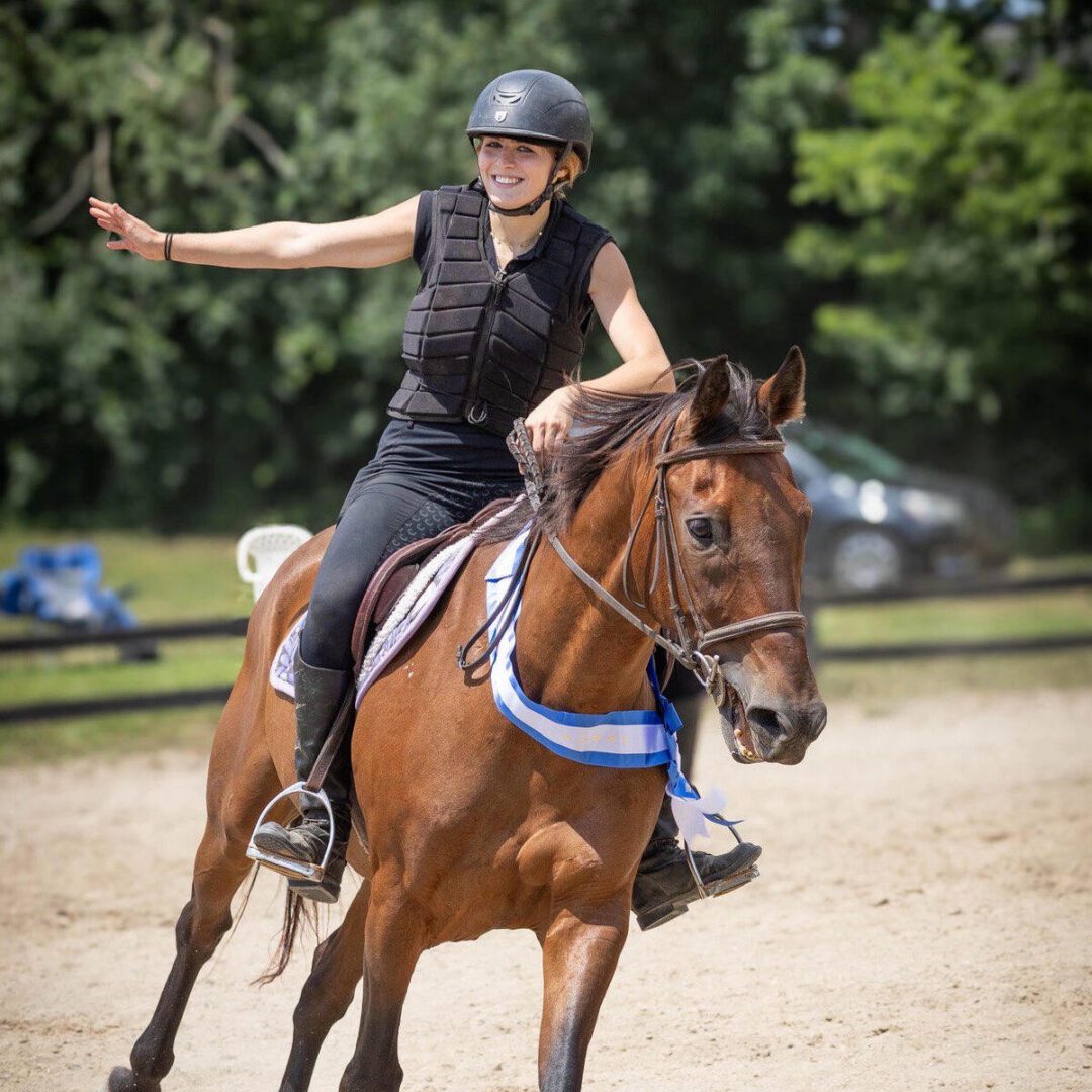Smiling equestrian on brown horse with blue ribbon